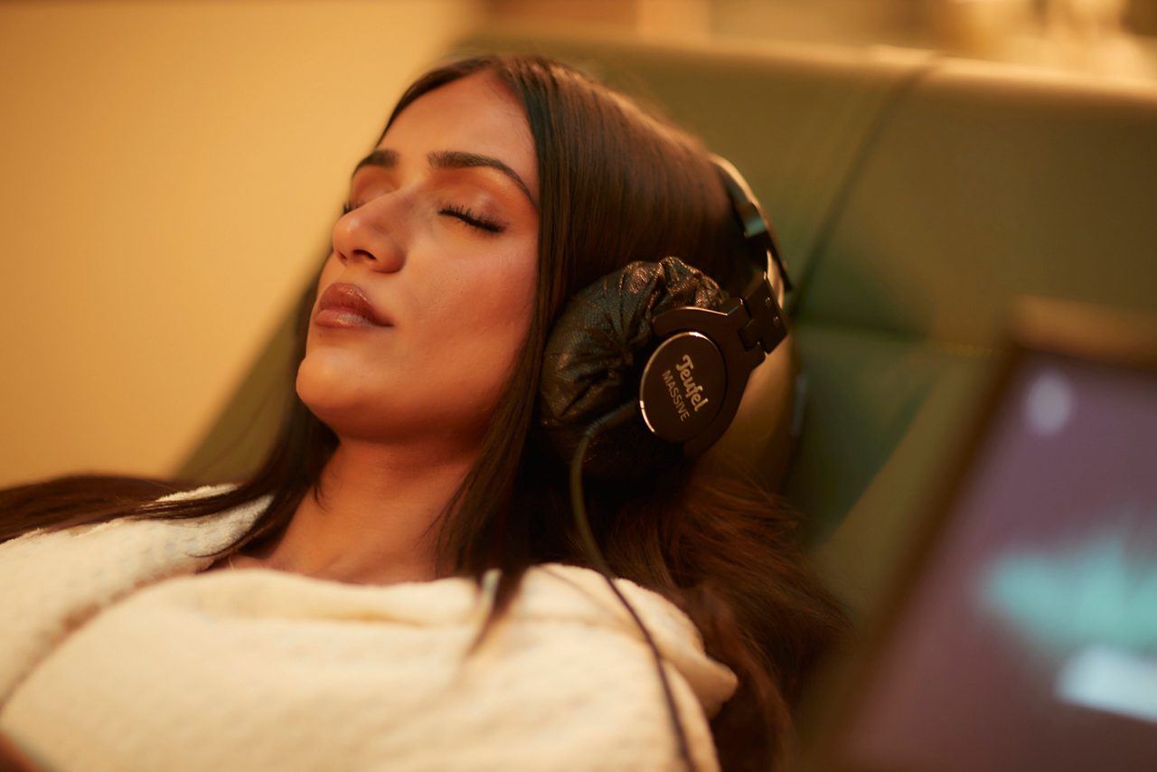 Woman wearing headphones, laid back in the Forest Serenity Suite.