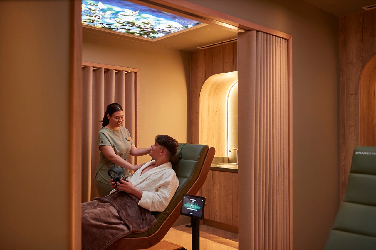 Man laid back in a comfortable chair talking with a spa therapist.