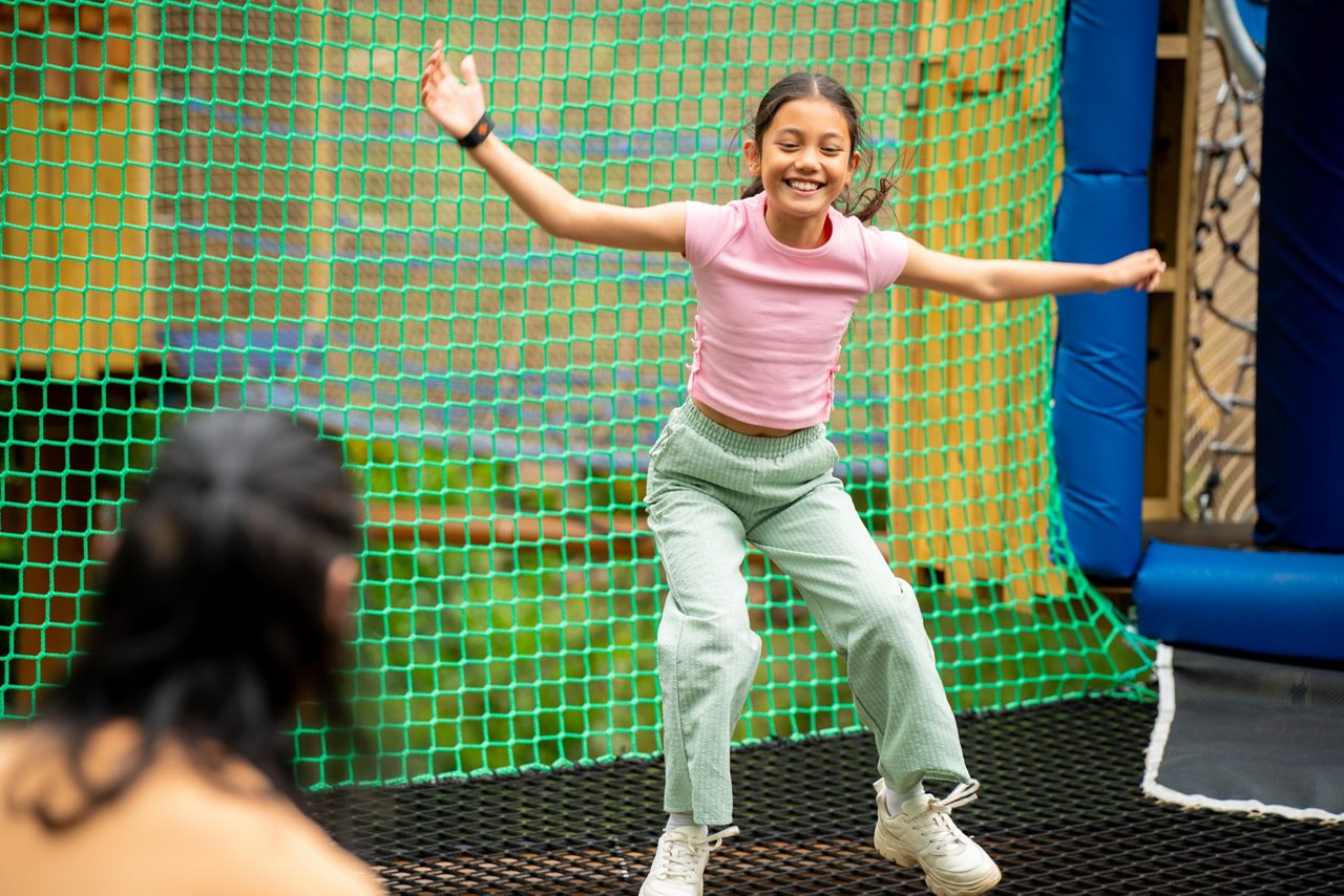 lady on aerial adventure going down a zip line over the lake. she is smiling and waving her hands in the air