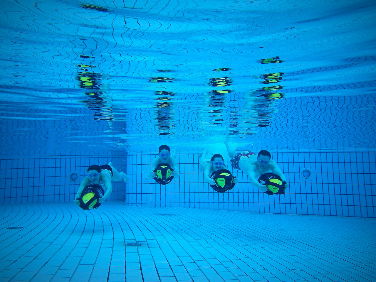 5 childrean below the water pushing Aqua Jets through the pool.