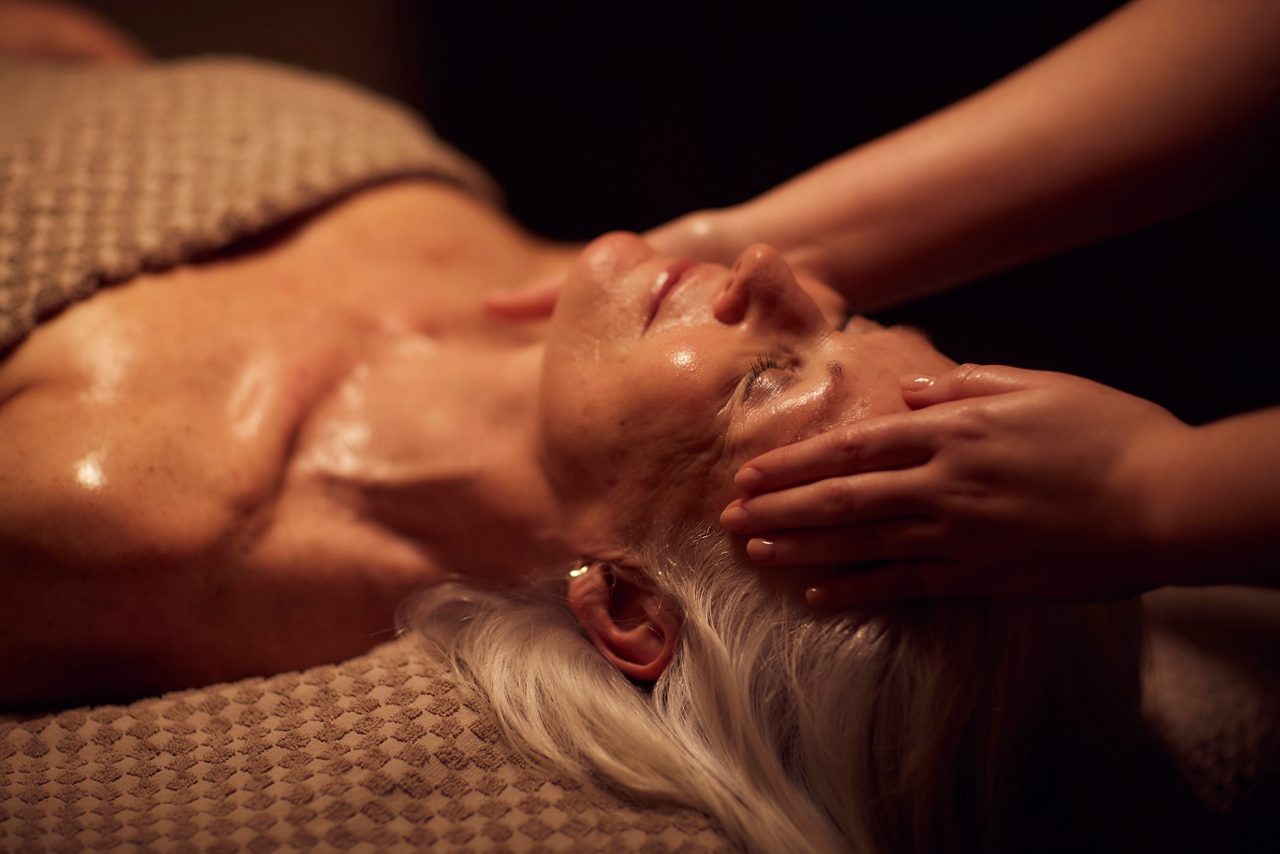 Spa therapist giving a woman a facial treatment.