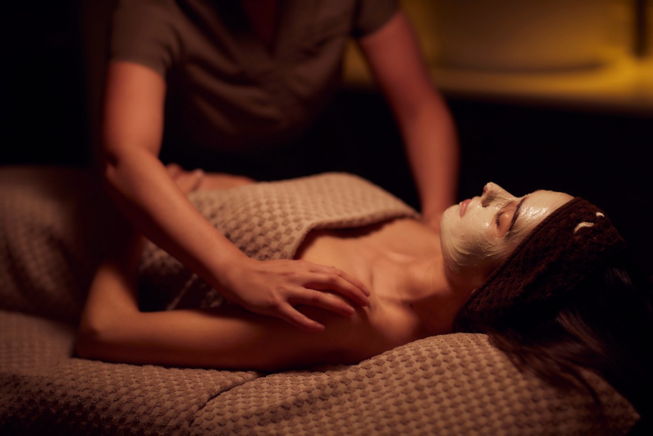 Spa therapist giving a woman a face mask treatment.
