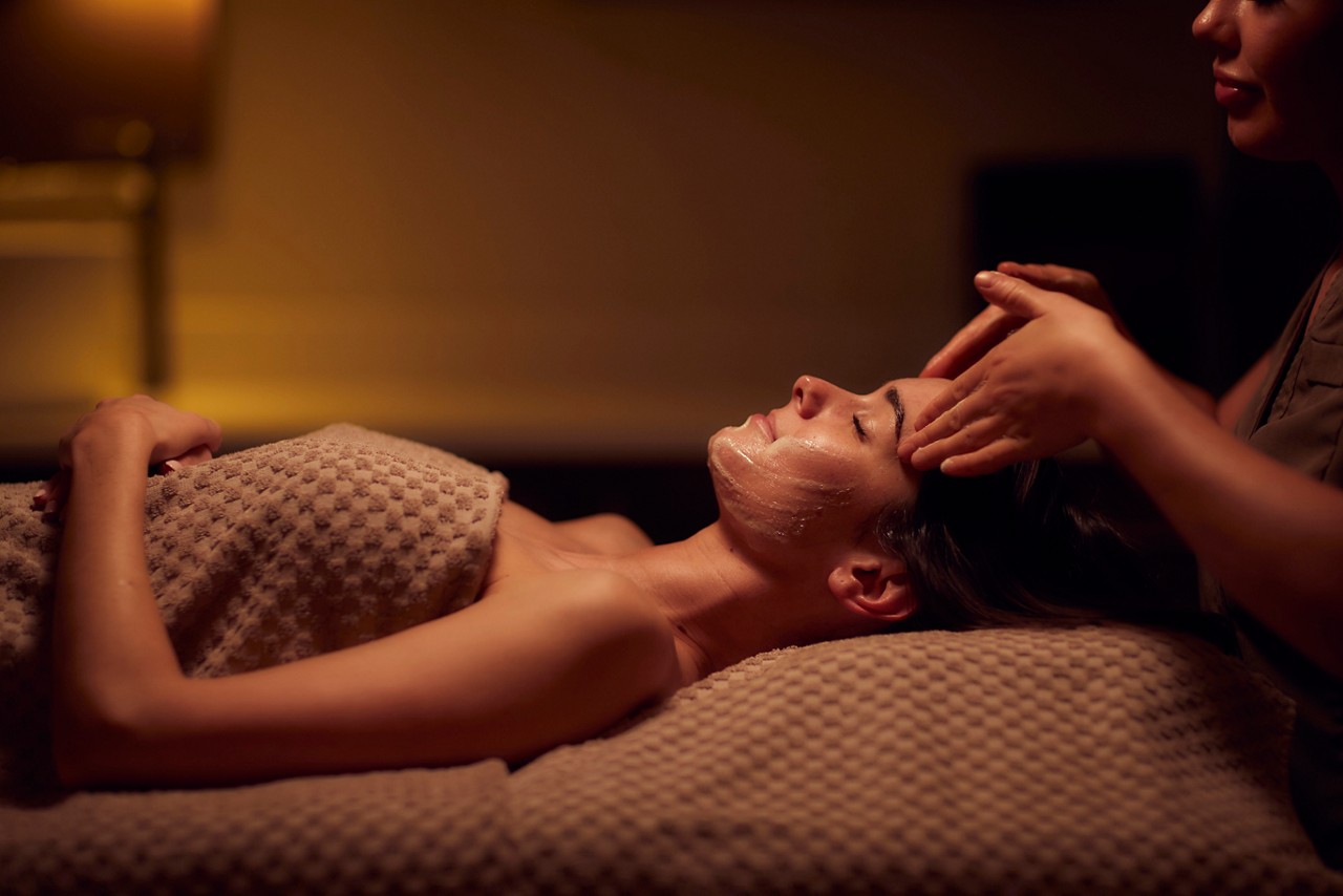 Spa therapist giving a woman a facial treatment.