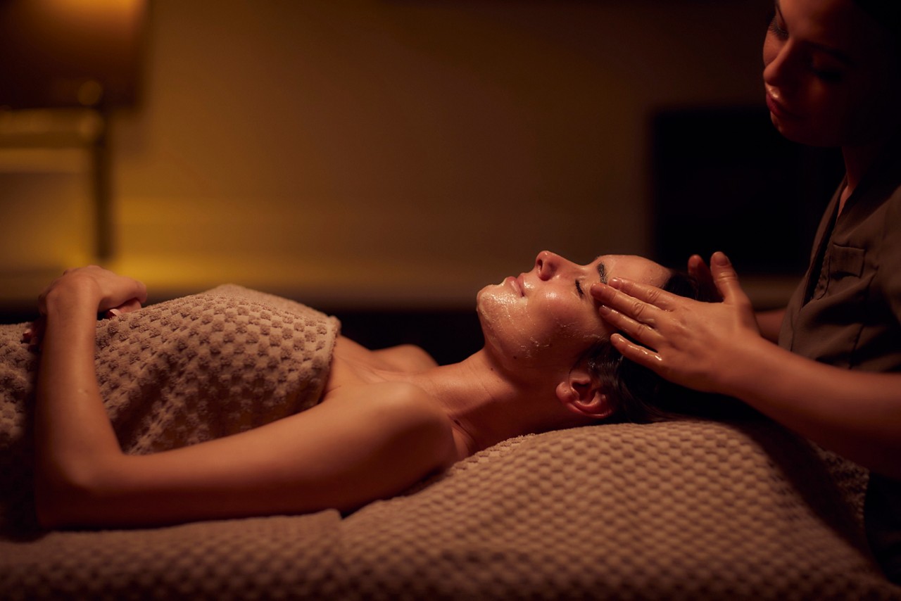 Spa therapist giving a woman a facial treatment.