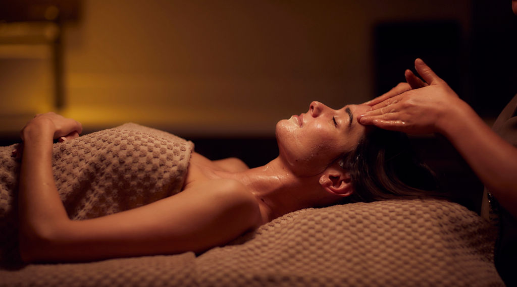 Spa therapist giving a woman a facial treatment.