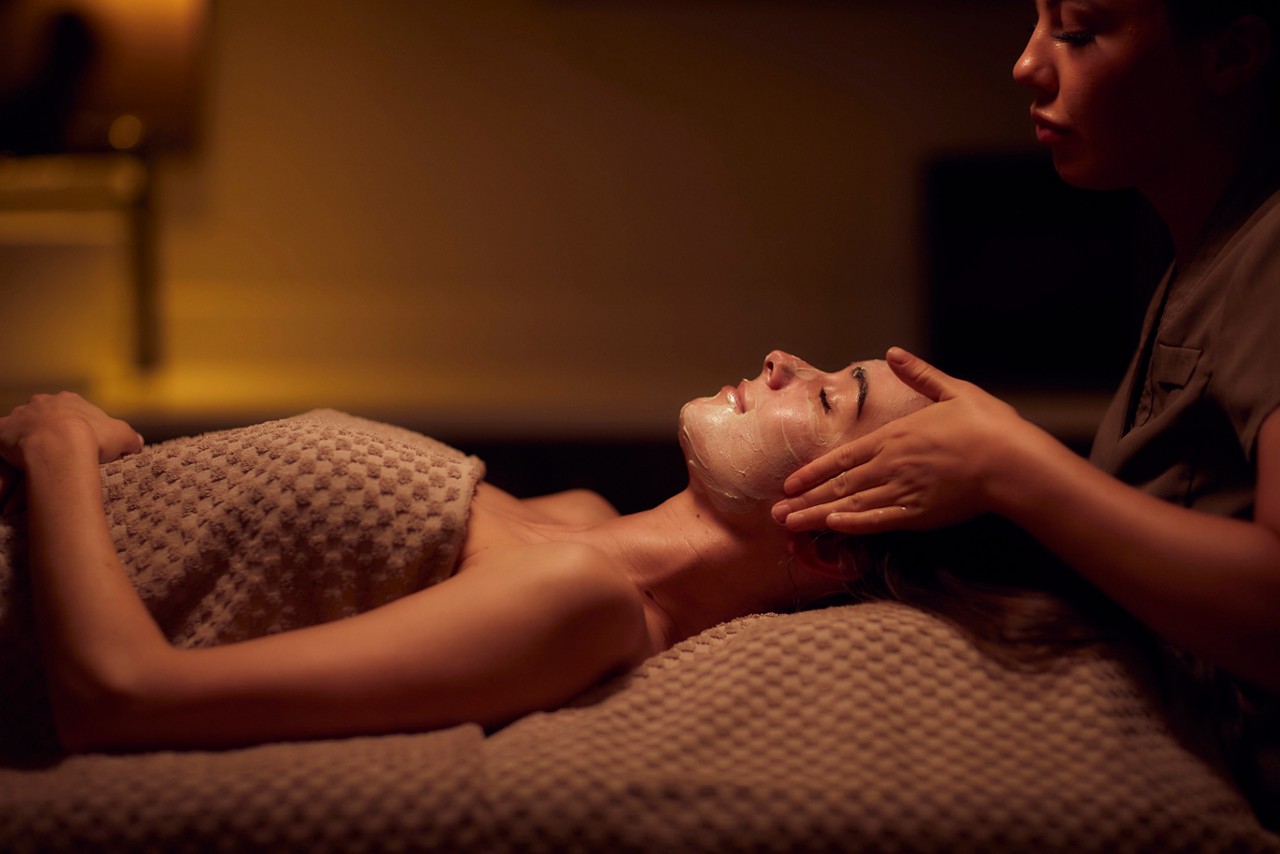Spa therapist giving a woman a facial treatment.