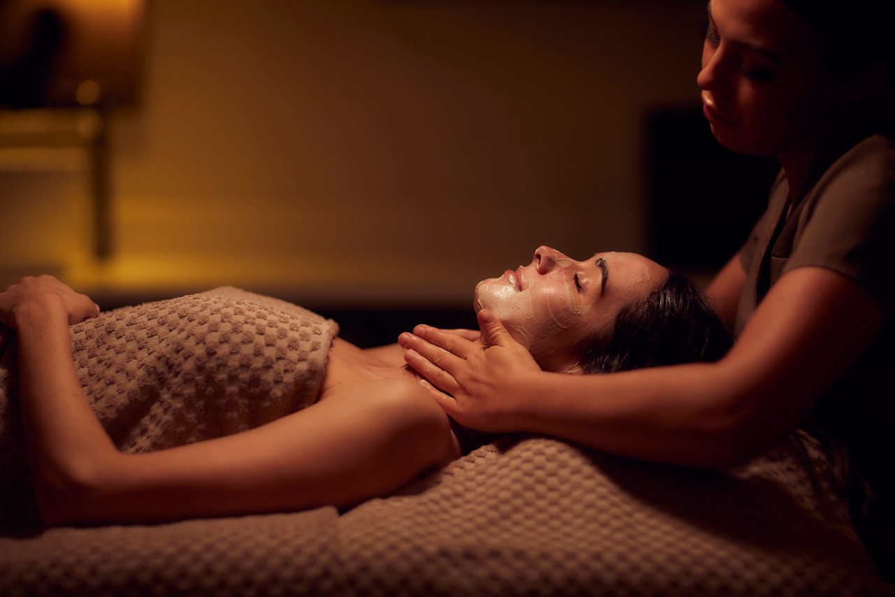 Spa therapist giving a woman a facial treatment.