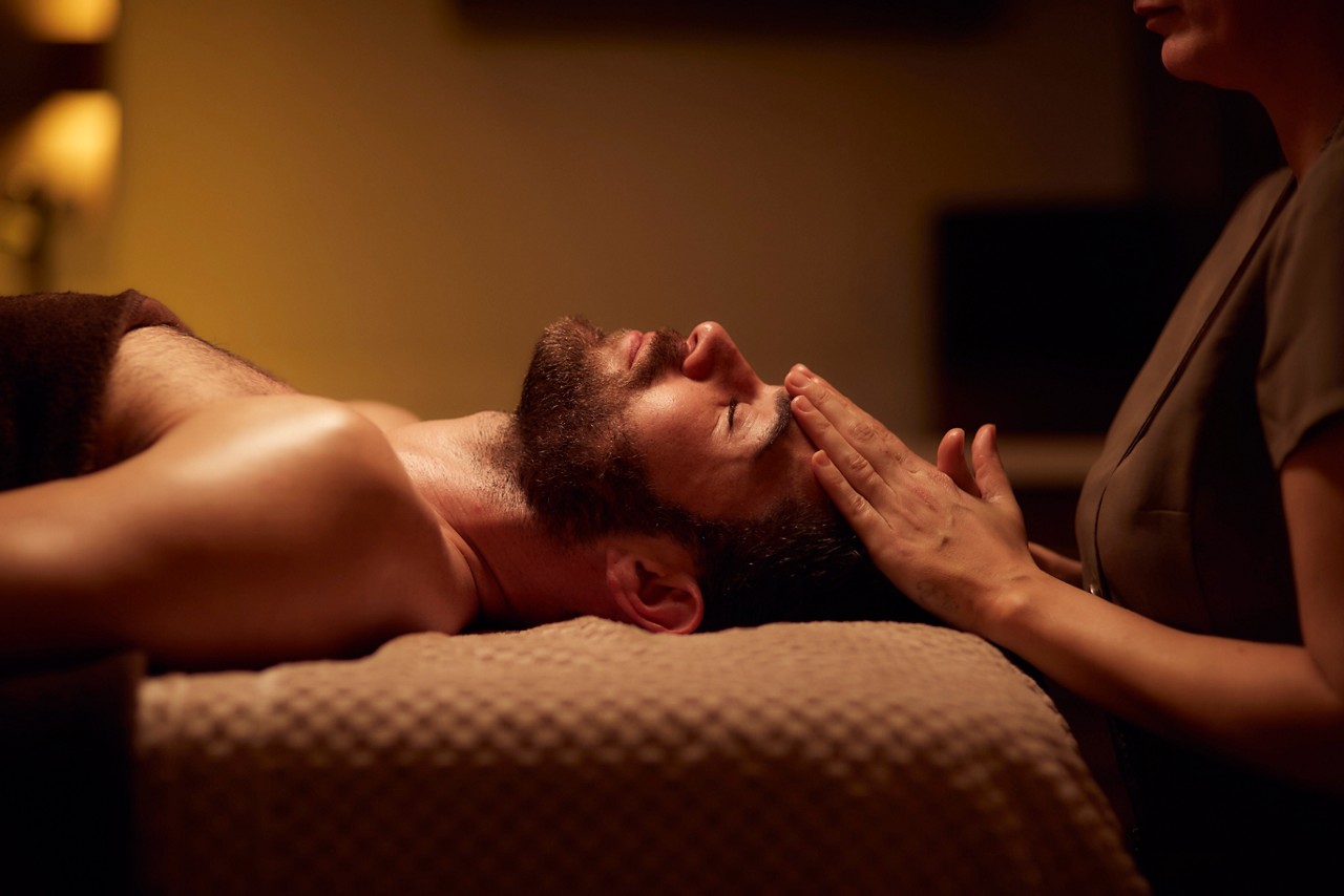 Spa therapist giving a man a relaxing facial treatment.