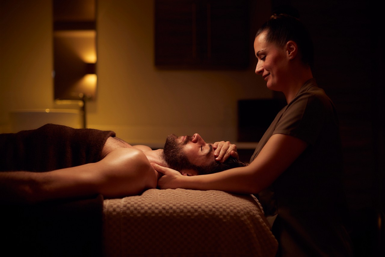 Spa therapist giving a man a relaxing facial treatment.
