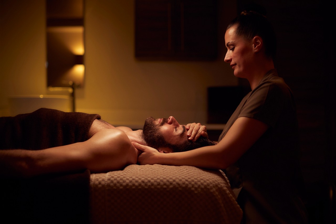 Spa therapist giving a man a relaxing facial treatment.