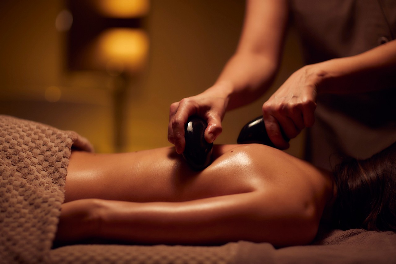 Spa therapist giving a woman a Thermabliss hot stone body massage.