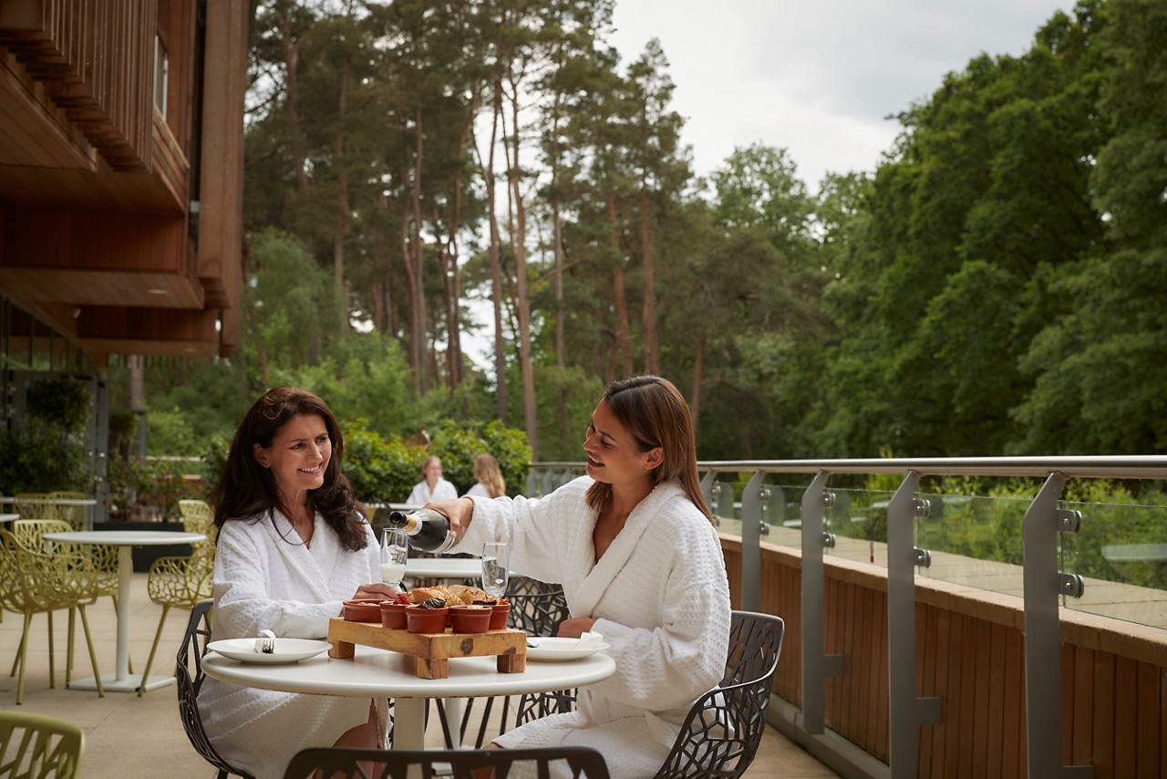 Two ladies sharing a Vitalé Platter on a balcony surrounded by the forest.