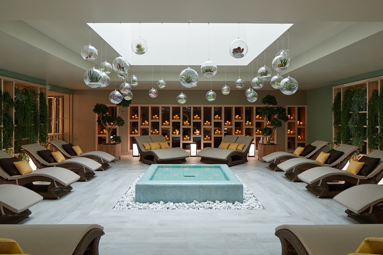 Cushioned lounging beds surrounding a tiled water feature inside the Forest Garden.