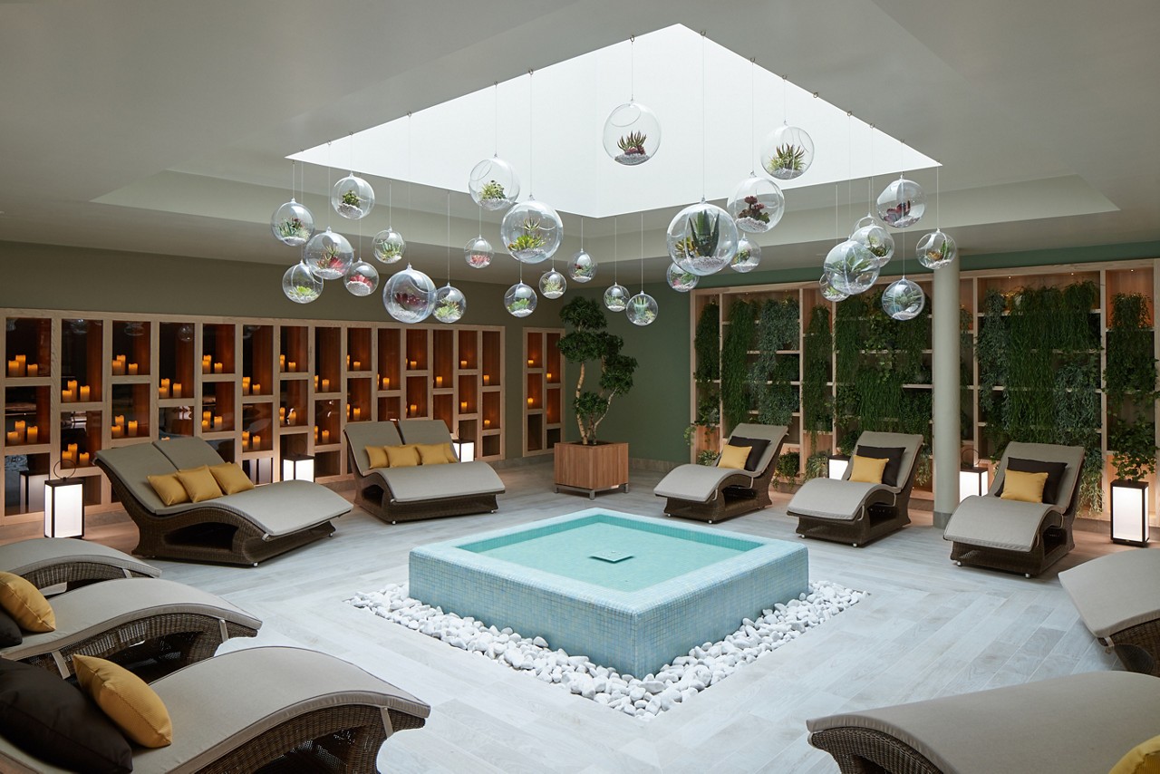 Cushioned lounging beds surrounding a tiled water feature inside the Forest Garden.