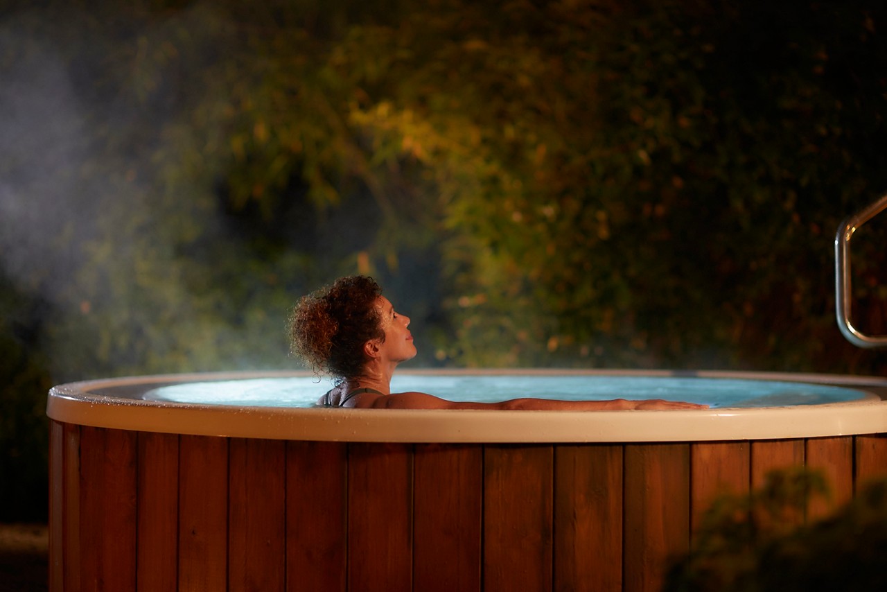 Woman soaking in a bubbling outdoor hot tub.
