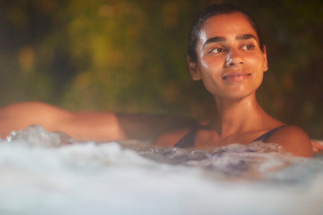 Woman soaking in a steamy outdoor hot tub.
