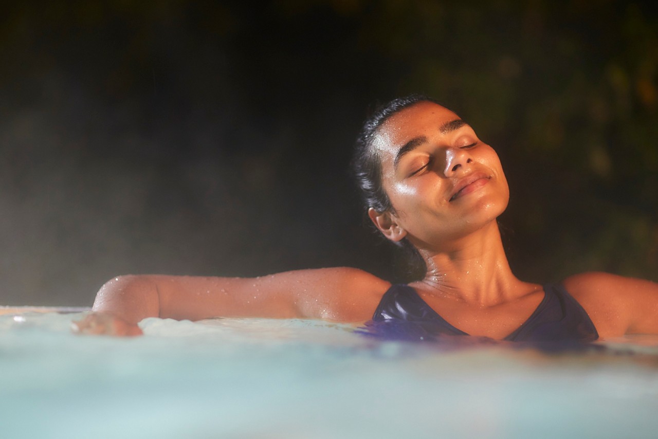 Woman soaking in a steamy outdoor hot tub.