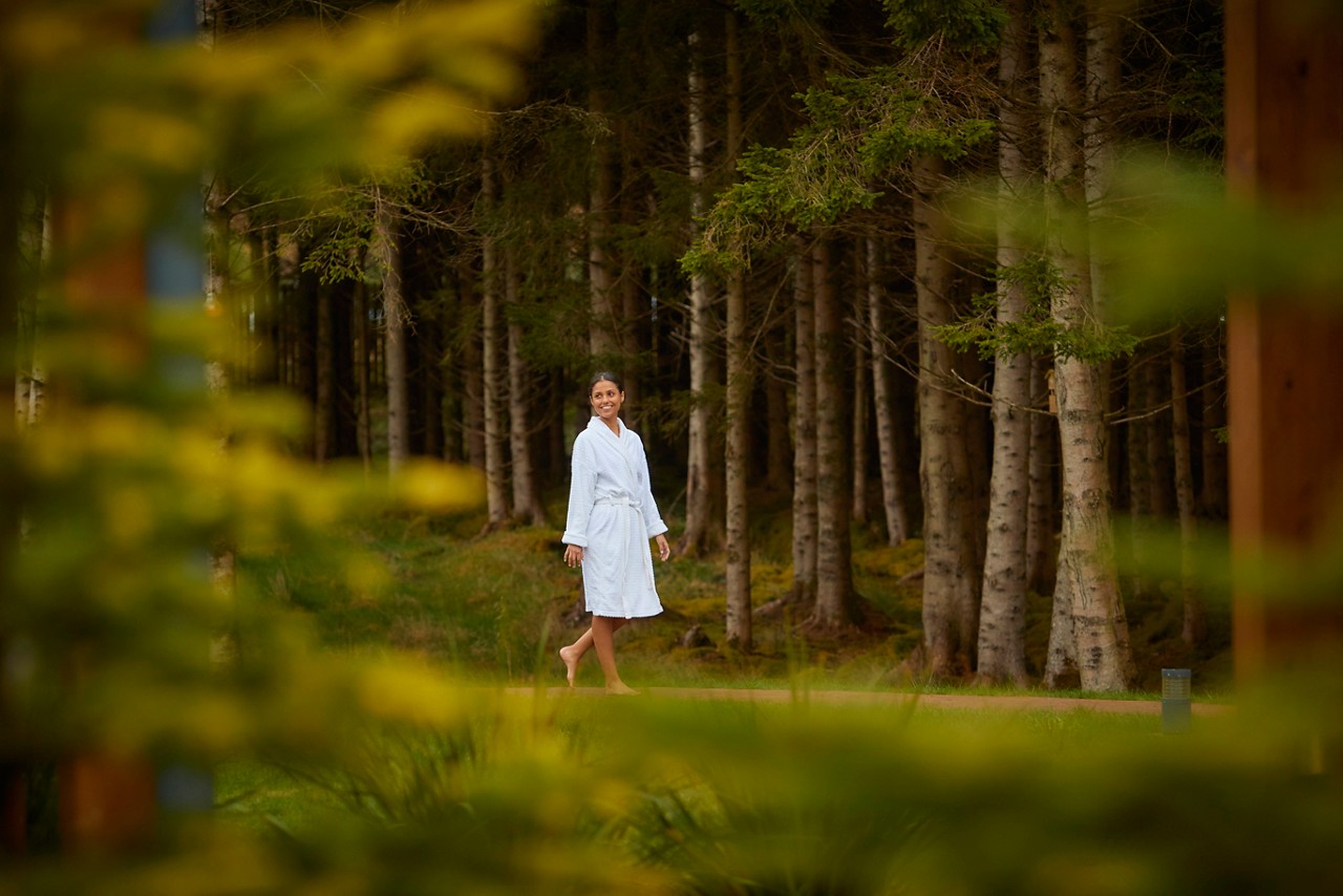 Woman walking through the forest in a fluffy spa robe.