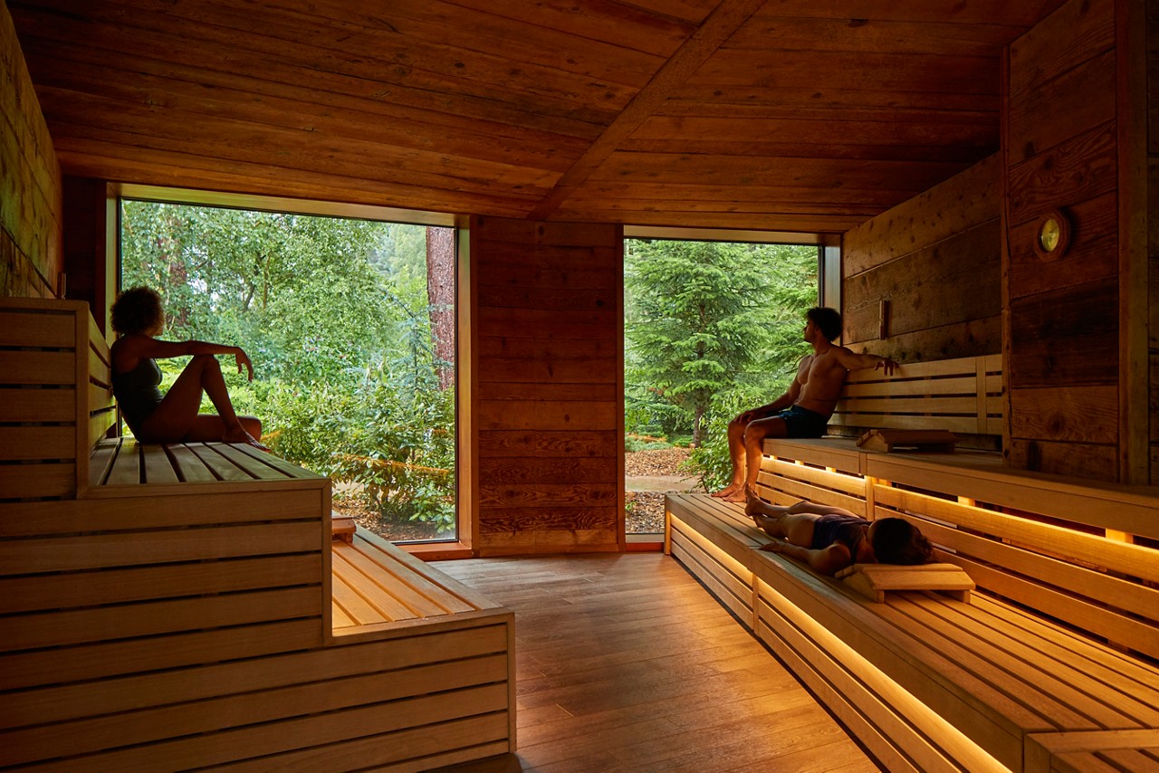 Man and woman sitting enjoying the forest views from inside the Nordic Sauna.