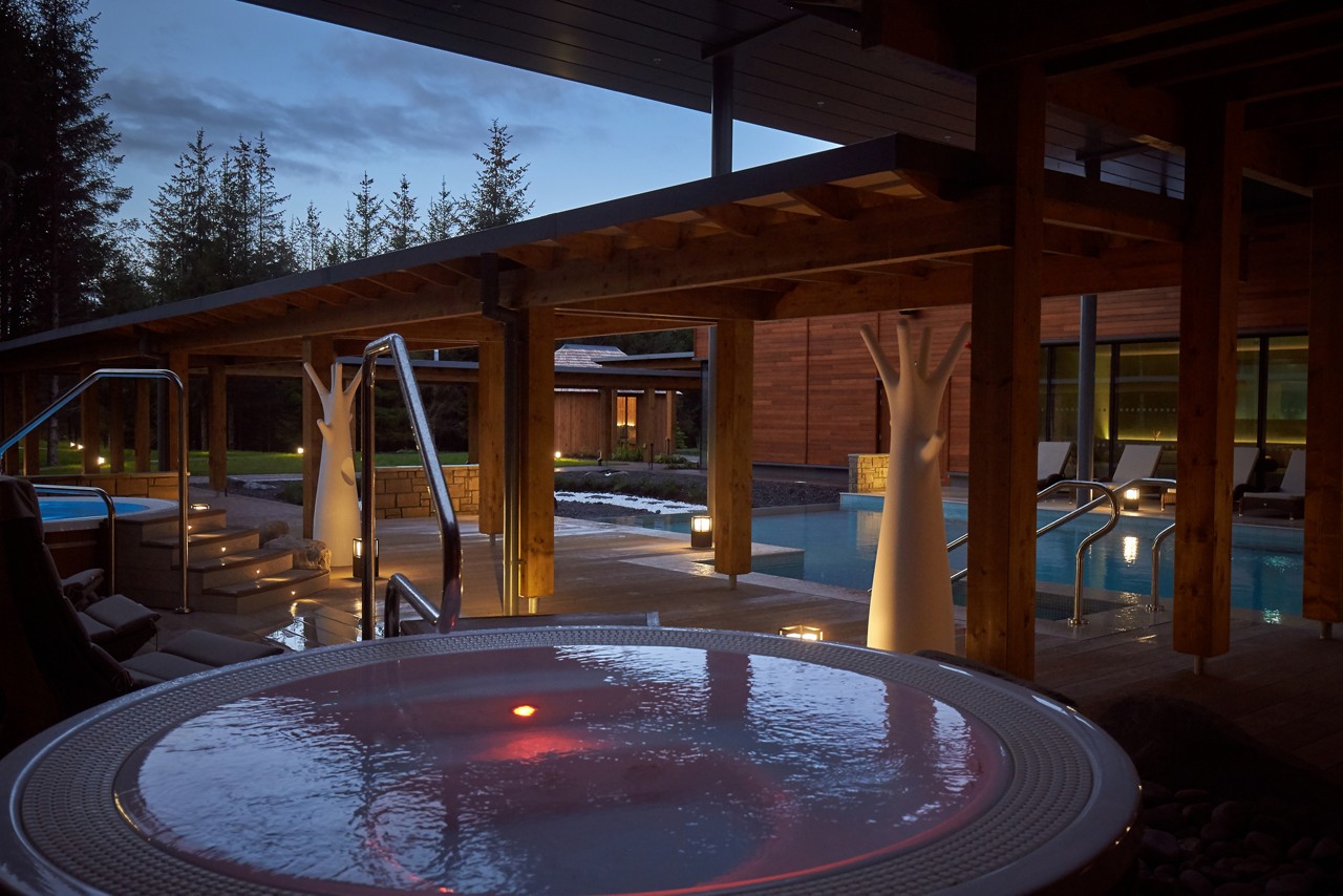 Outdoor hot tub in the evening surrounded by the forest. 