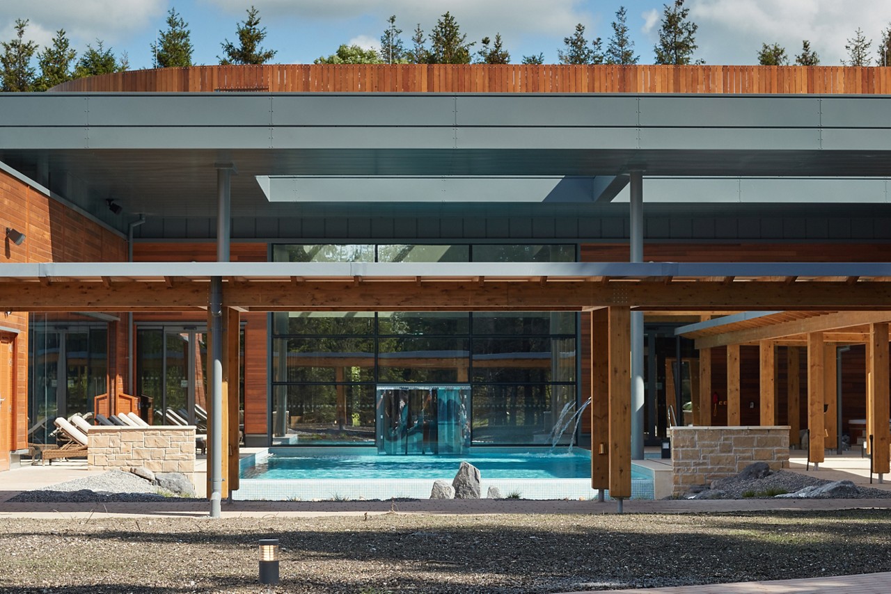 Glistening Outdoor Pool lined with sun loungers behind a wooden pergola.