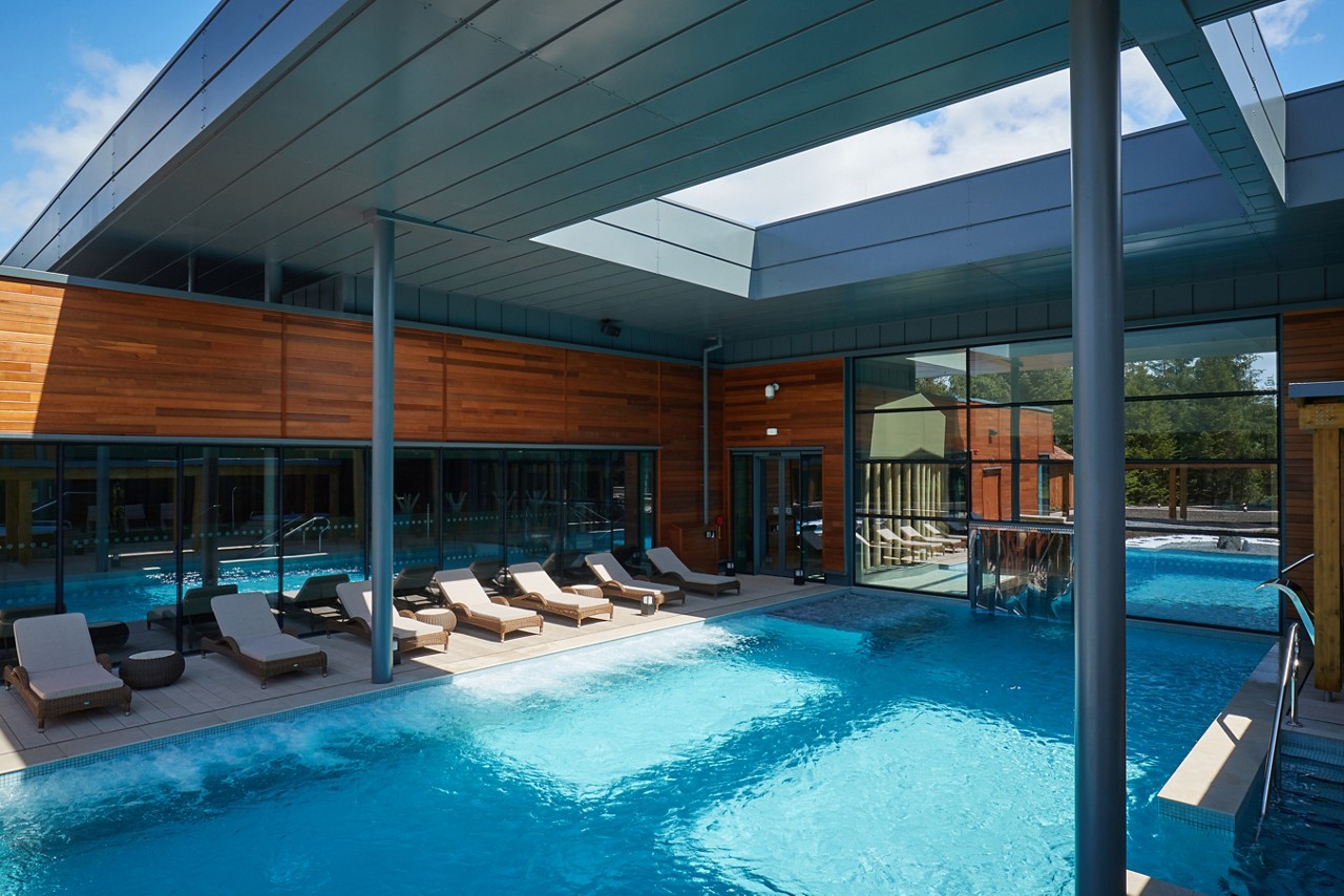 The sun reflecting on an Outdoor Pool surrounded by sun loungers.