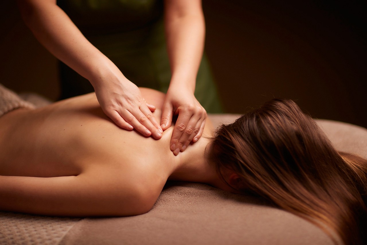 Spa therapist giving a woman a relaxing back massage body treatment.