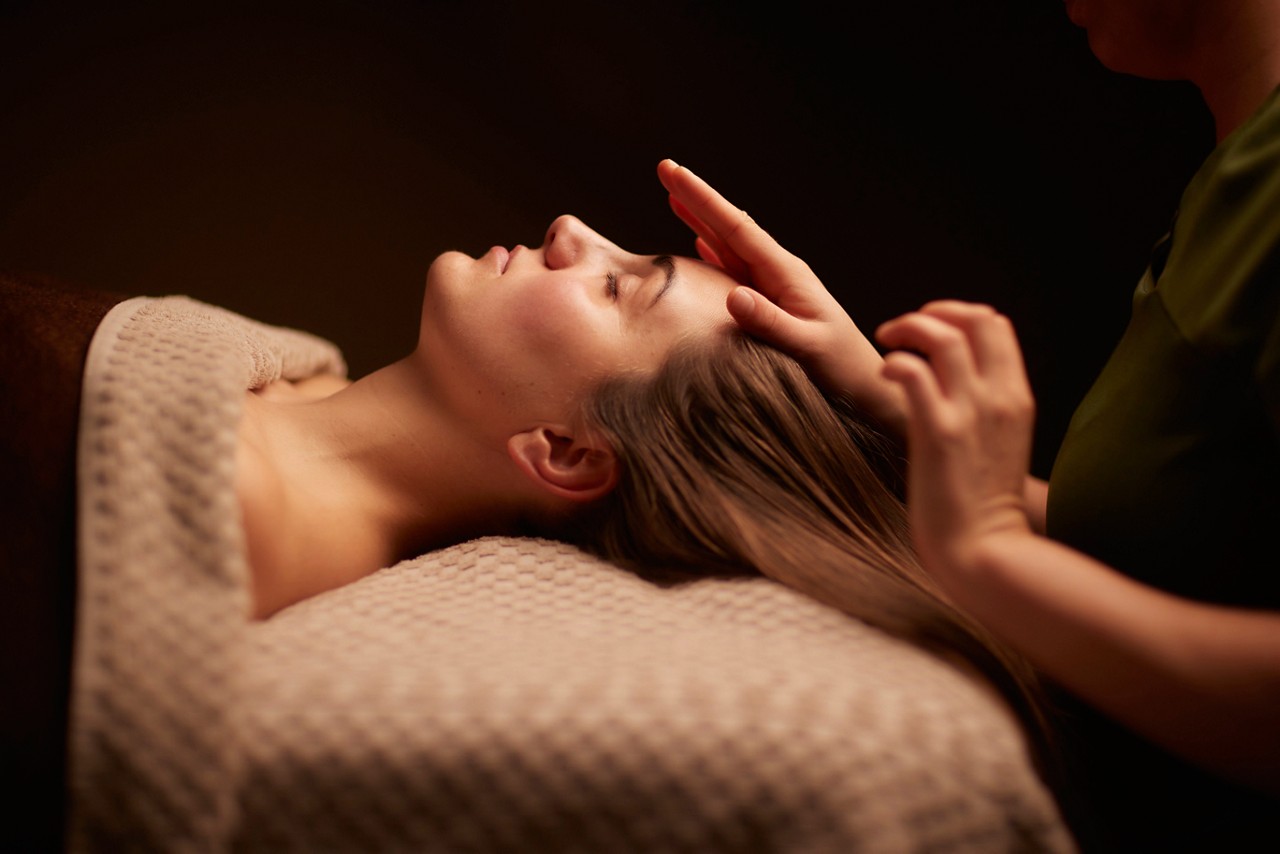 Spa therapist giving a woman a relaxing scalp massage.