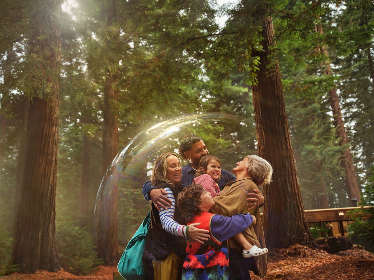 A family holding each other in a hug whilst surrounded by a bubble.