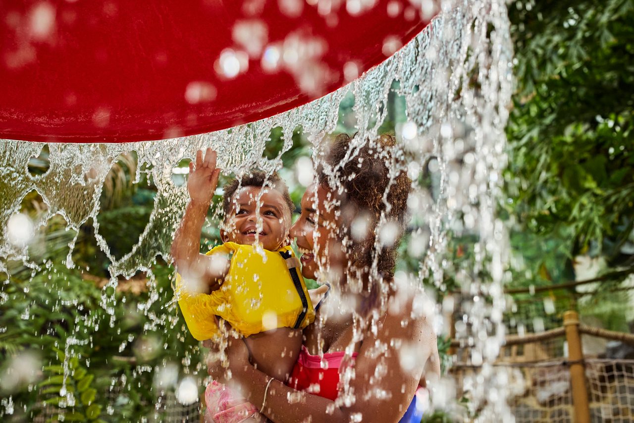 A little girl held by her dad in the splash pool.