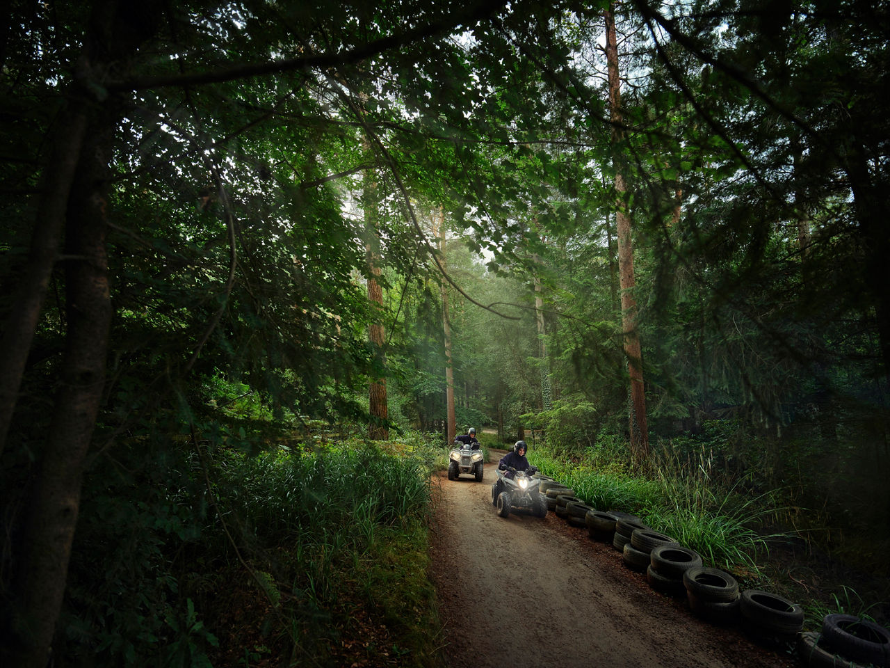 Two people quad biking in the heart of the forest.