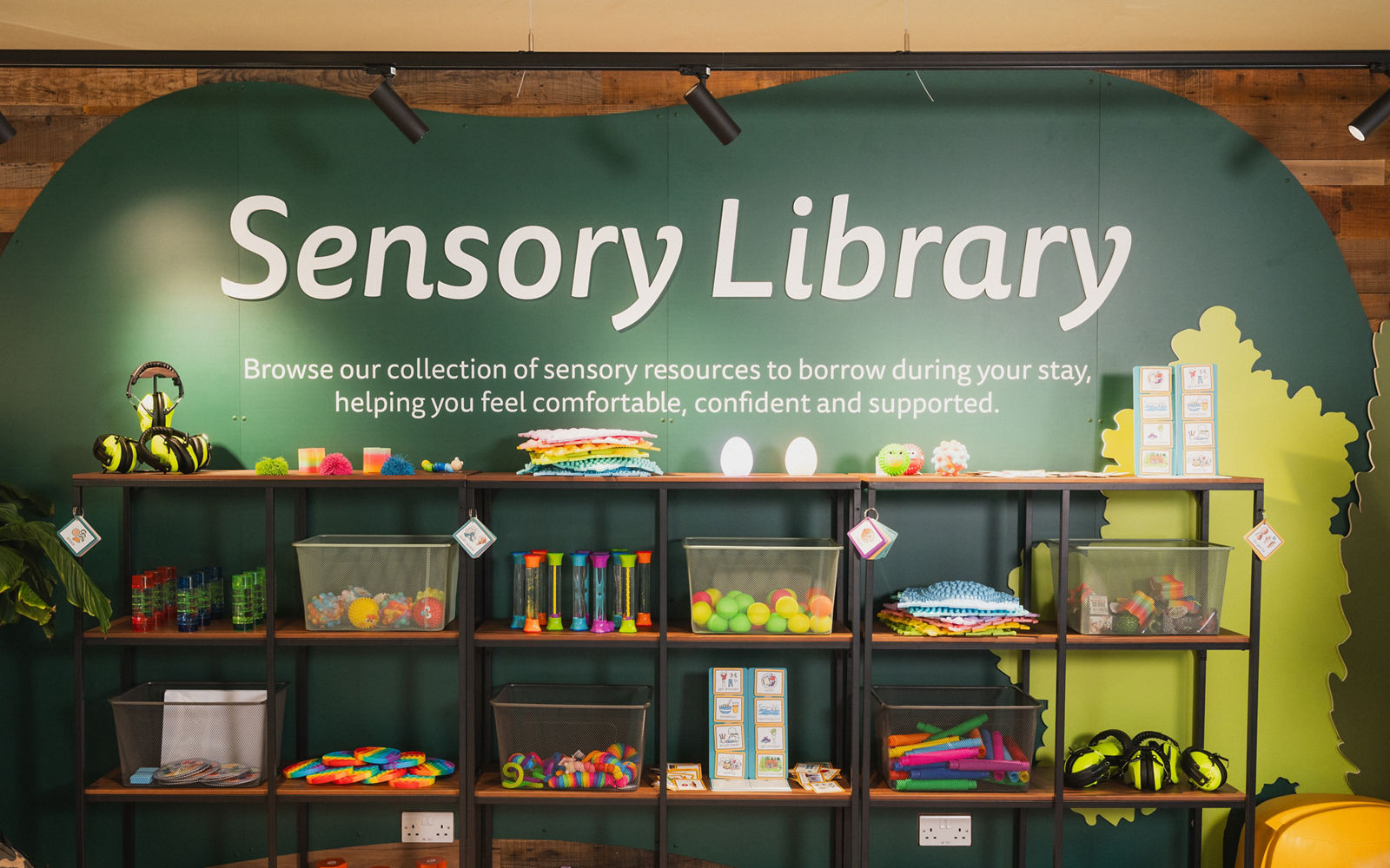 a green wall with shelves that host lots of different sensory toys on it