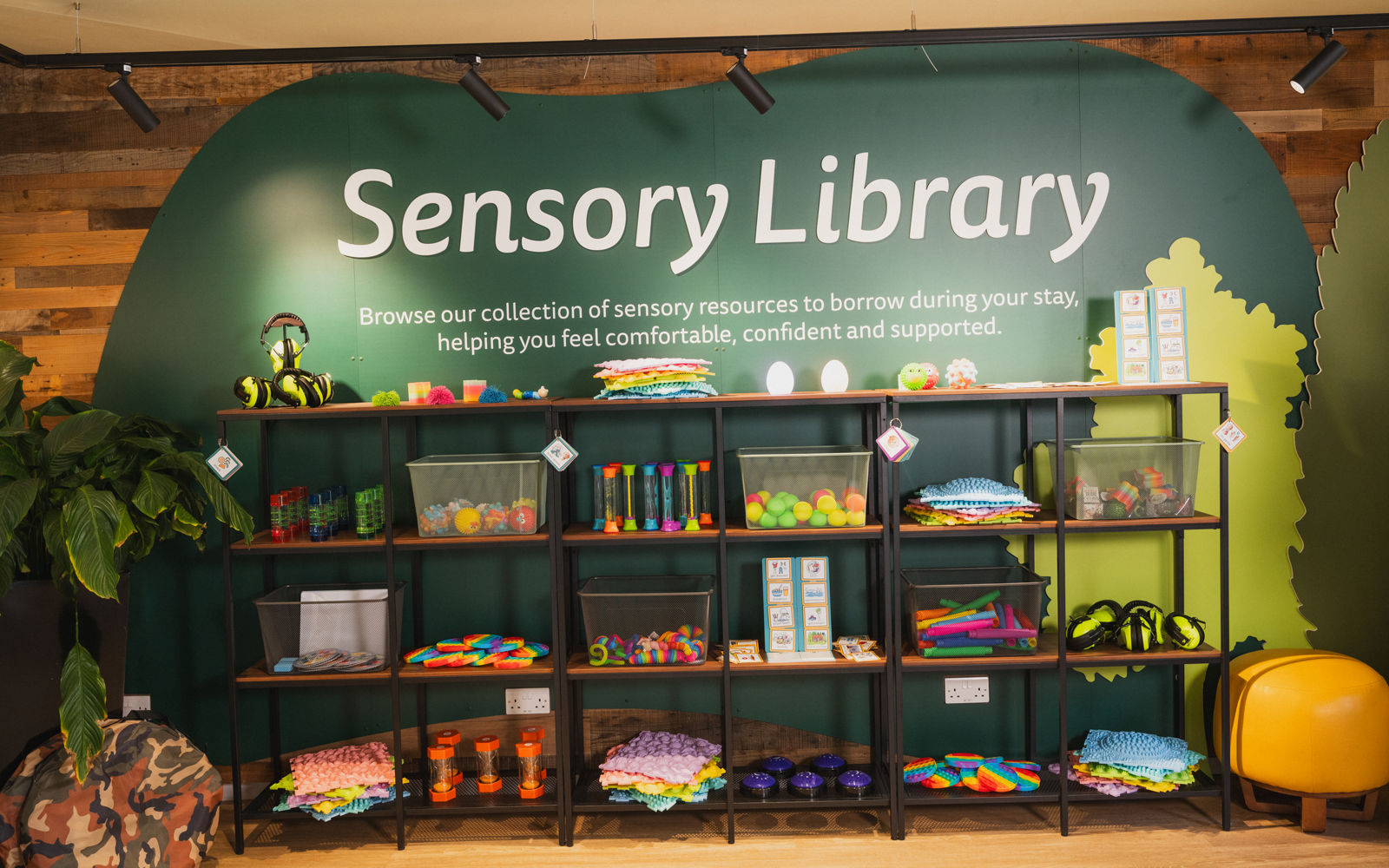 a green wall with shelves that host lots of different sensory toys on it