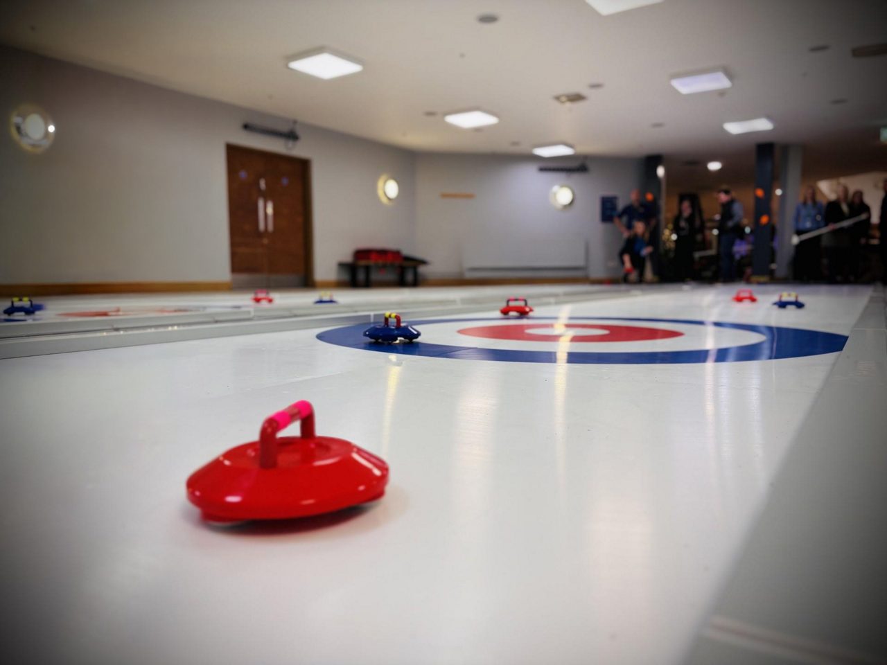 Curling equiptment on a shiny ice surface.