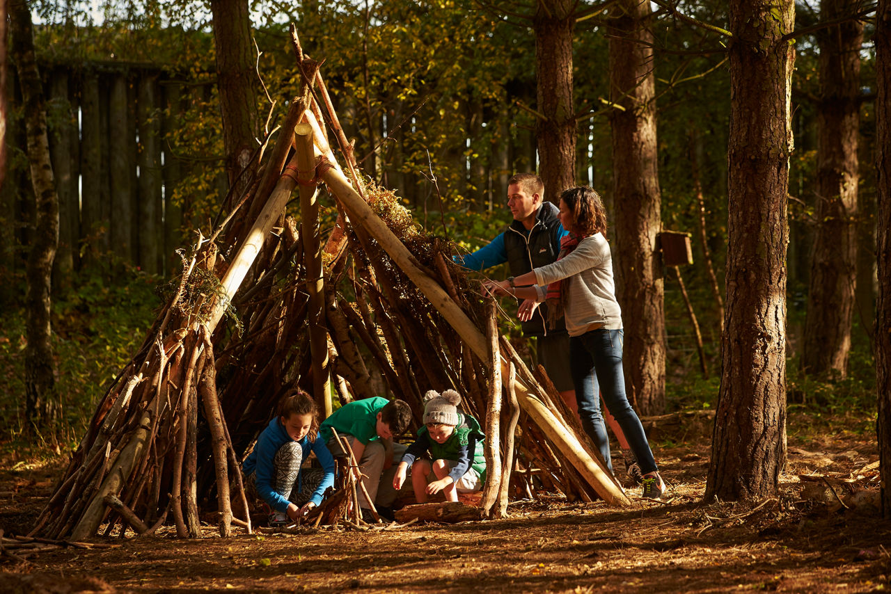 Family constructing a den in the forest.