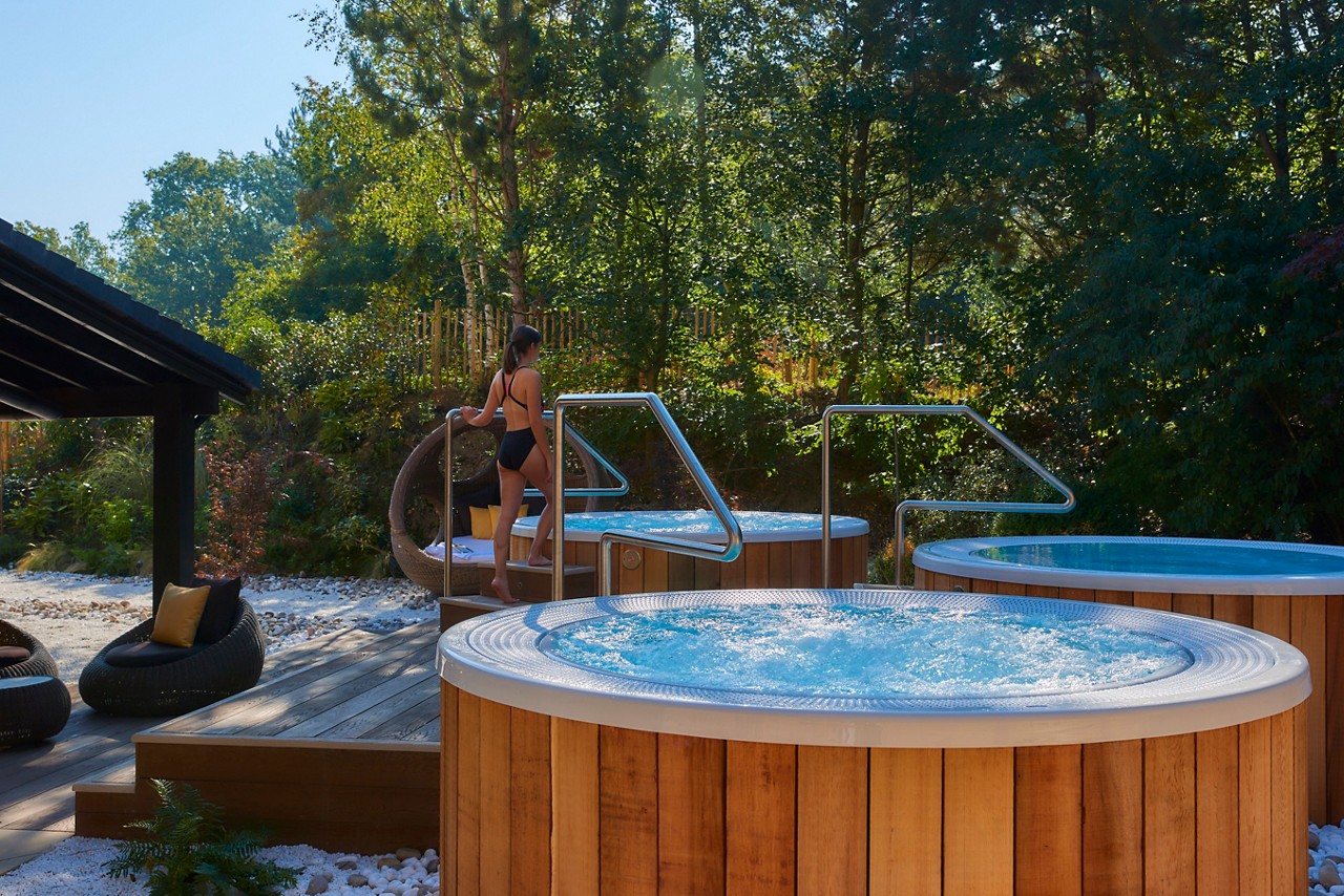 Woman stepping into a bubbling outdoor hot tub.
