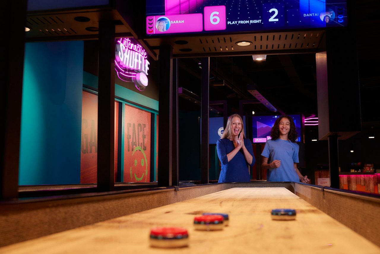 Two adults playing shuffleboard.