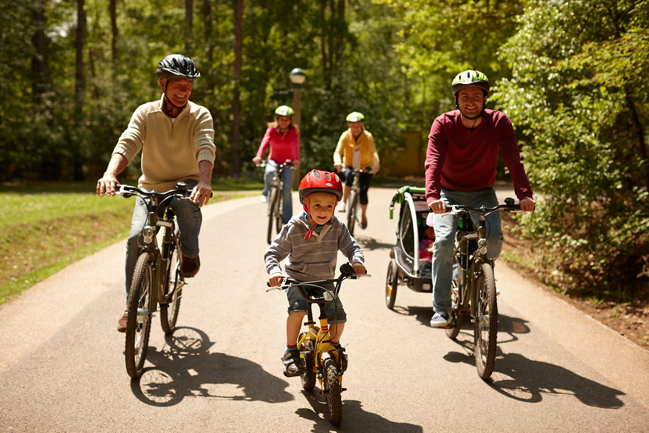 A multi-generational family cycling through the forest.