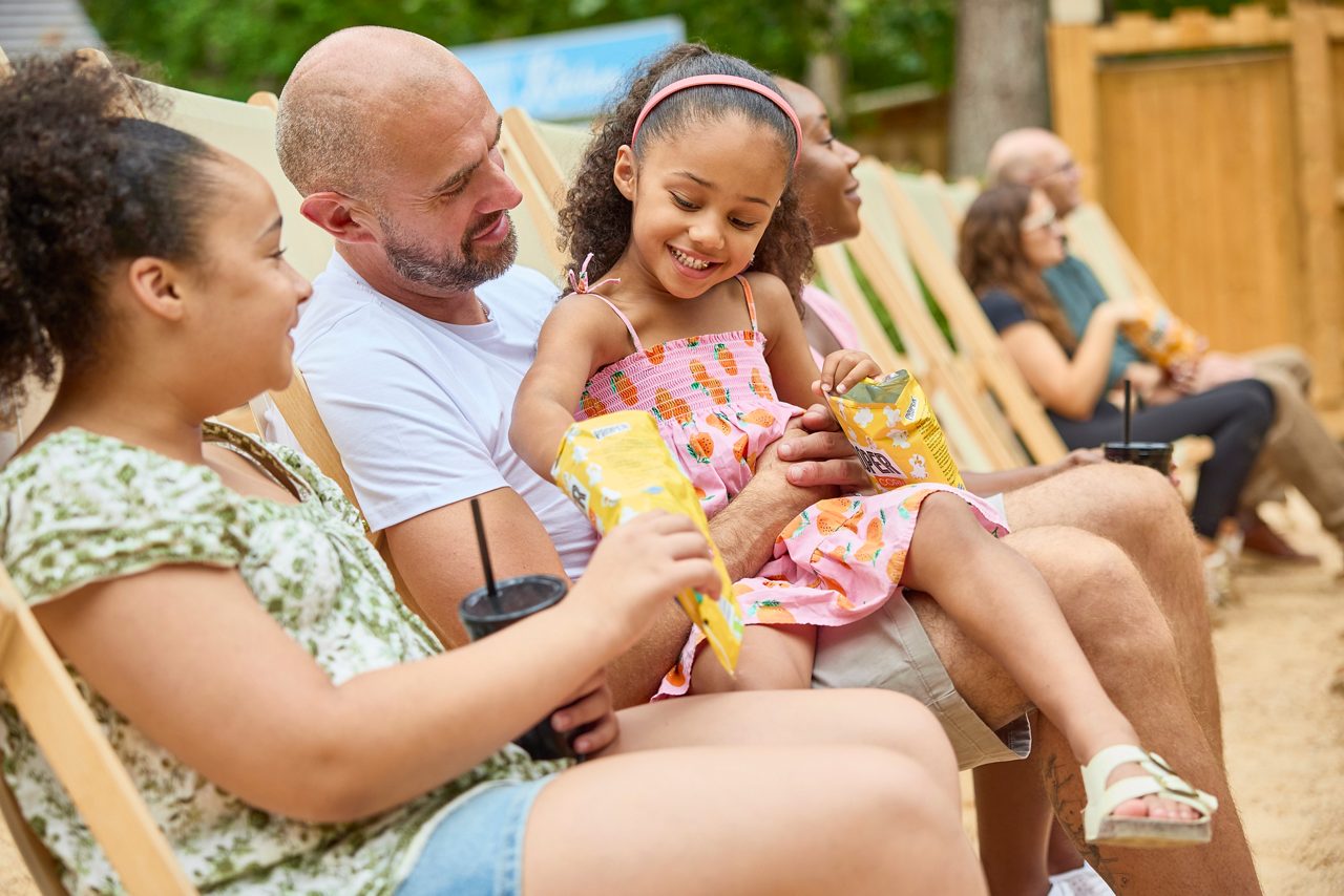 family sat on a beach in deck chairs