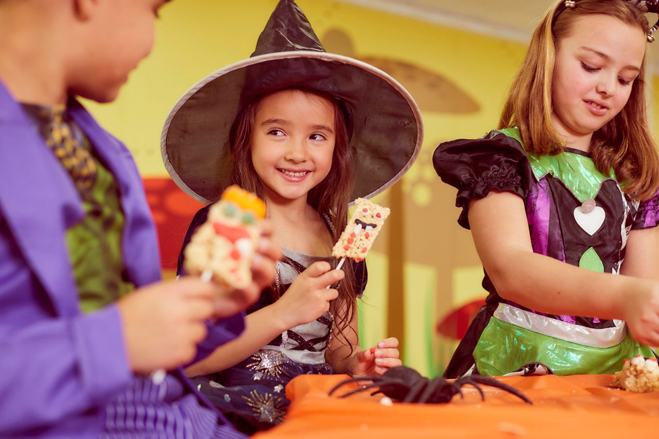 young boy dressed up in a halloween costume with a wizard hat on in front of a big spooky cauldron!