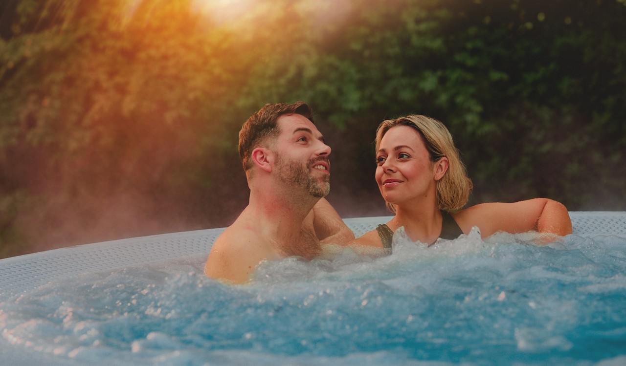 Couple soaking in an outdoor pool surrounded by the forest.
