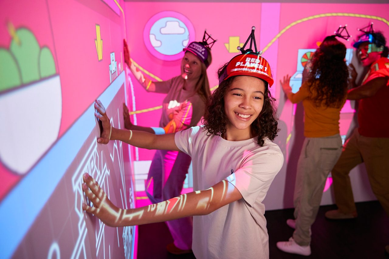 A girl taking part in the immersive gamebox game with pink interactive screens. 
