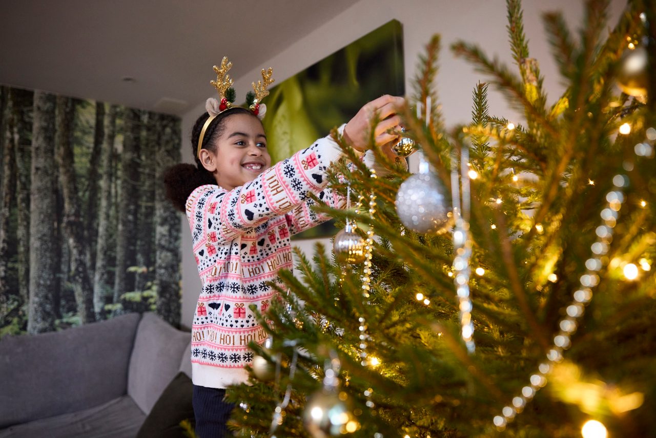 young girl decorating christmas tree