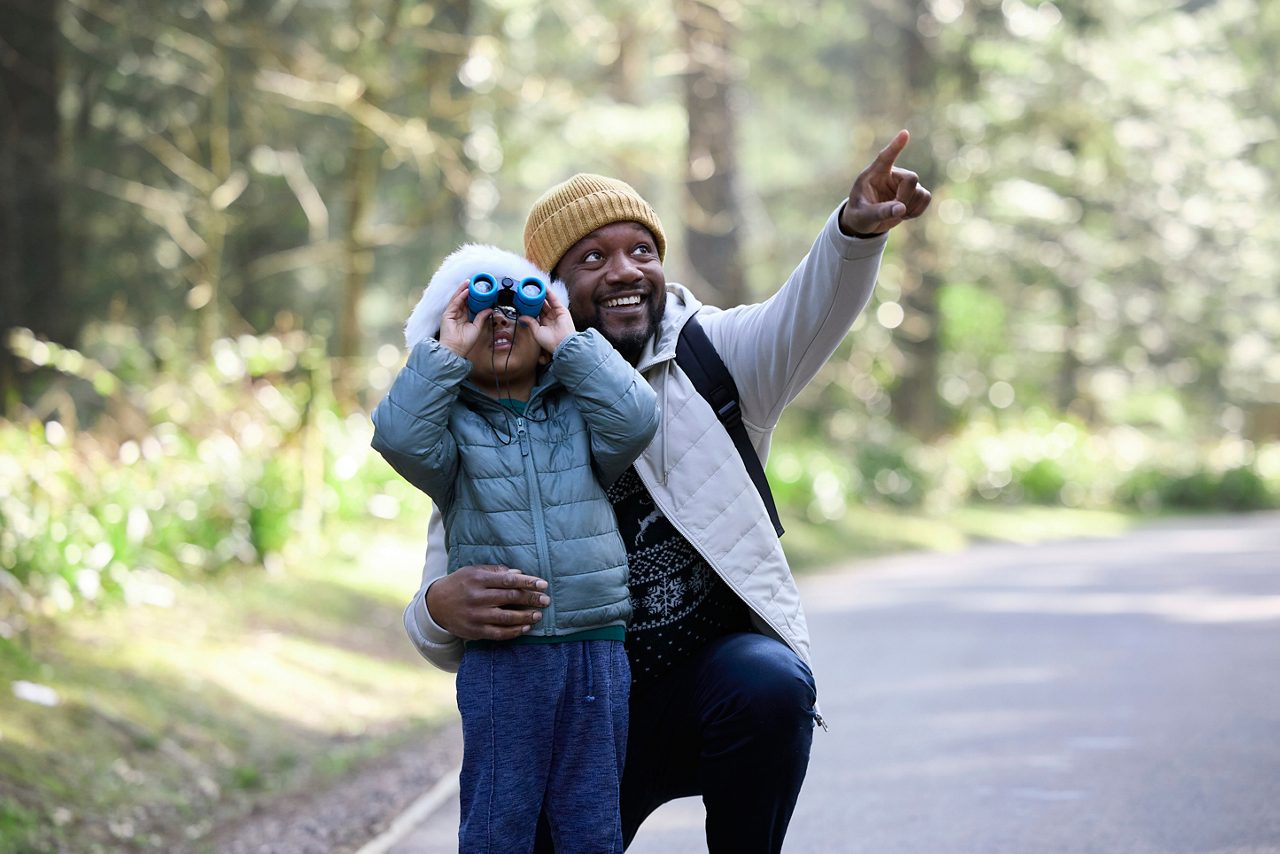 Man and son using binoculars to look at forest