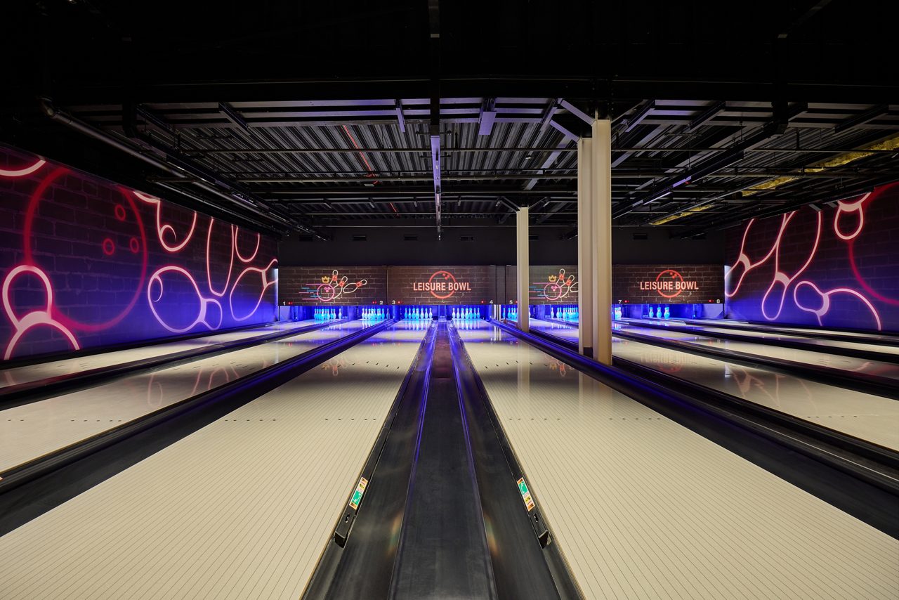 Bowling lanes with glowing artwork on the walls.