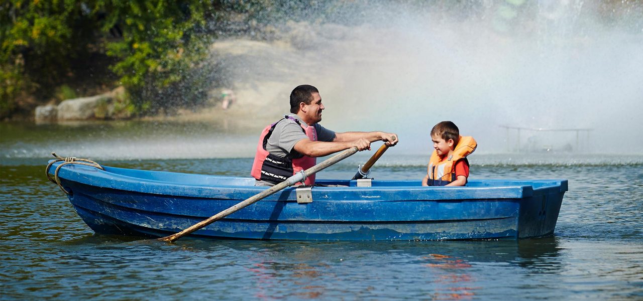 A father and son on a row boat on the lake