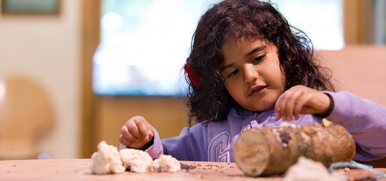 young girl making a bird feeder 