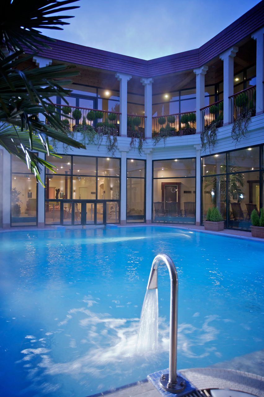 Water fountain flowing into an outdoor courtyard pool.
