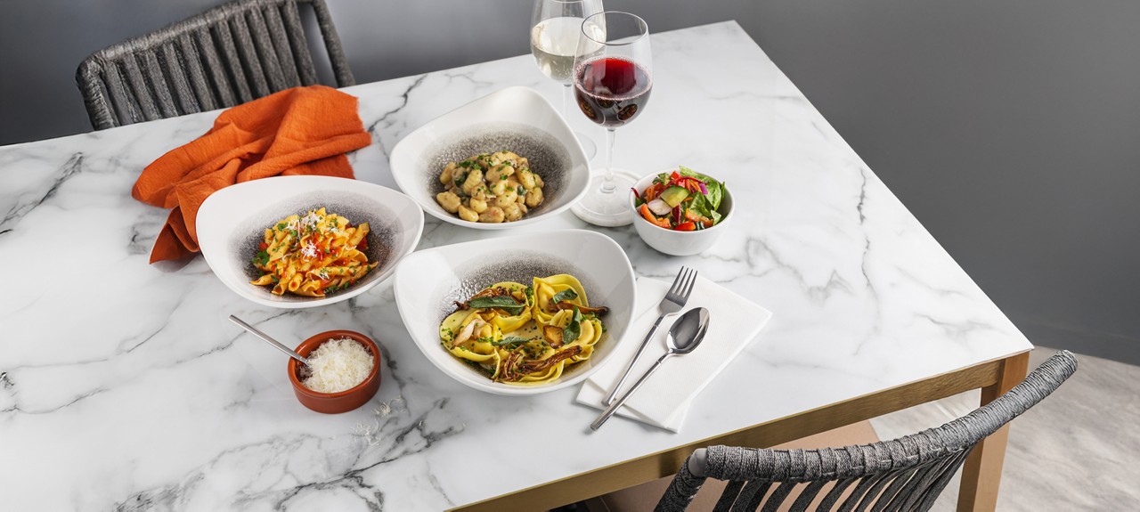 A selection of pasta dishes, served with a side salad.