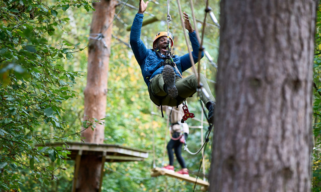 A man going down a zip wire on the Aerial Adventure.